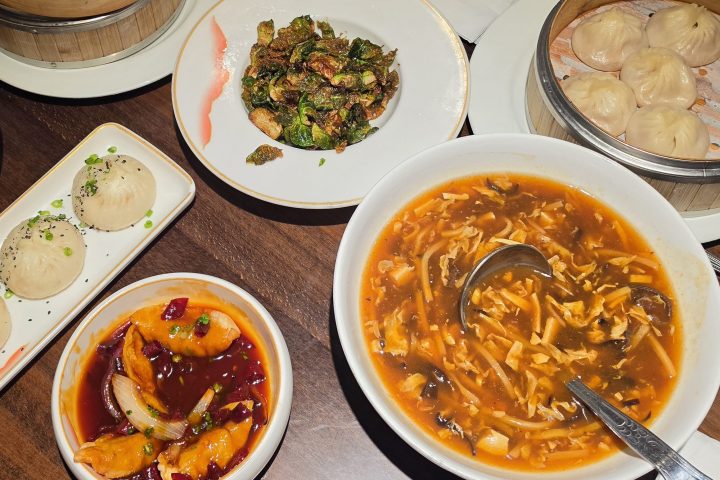 Assorted Chinese dishes, including dumplings, soup, and stir-fry on a wooden table.