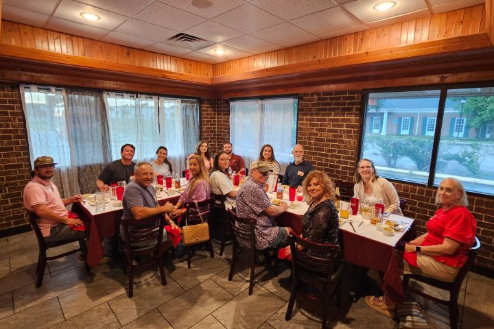 Group of people seated around a rectangular table in a restaurant.