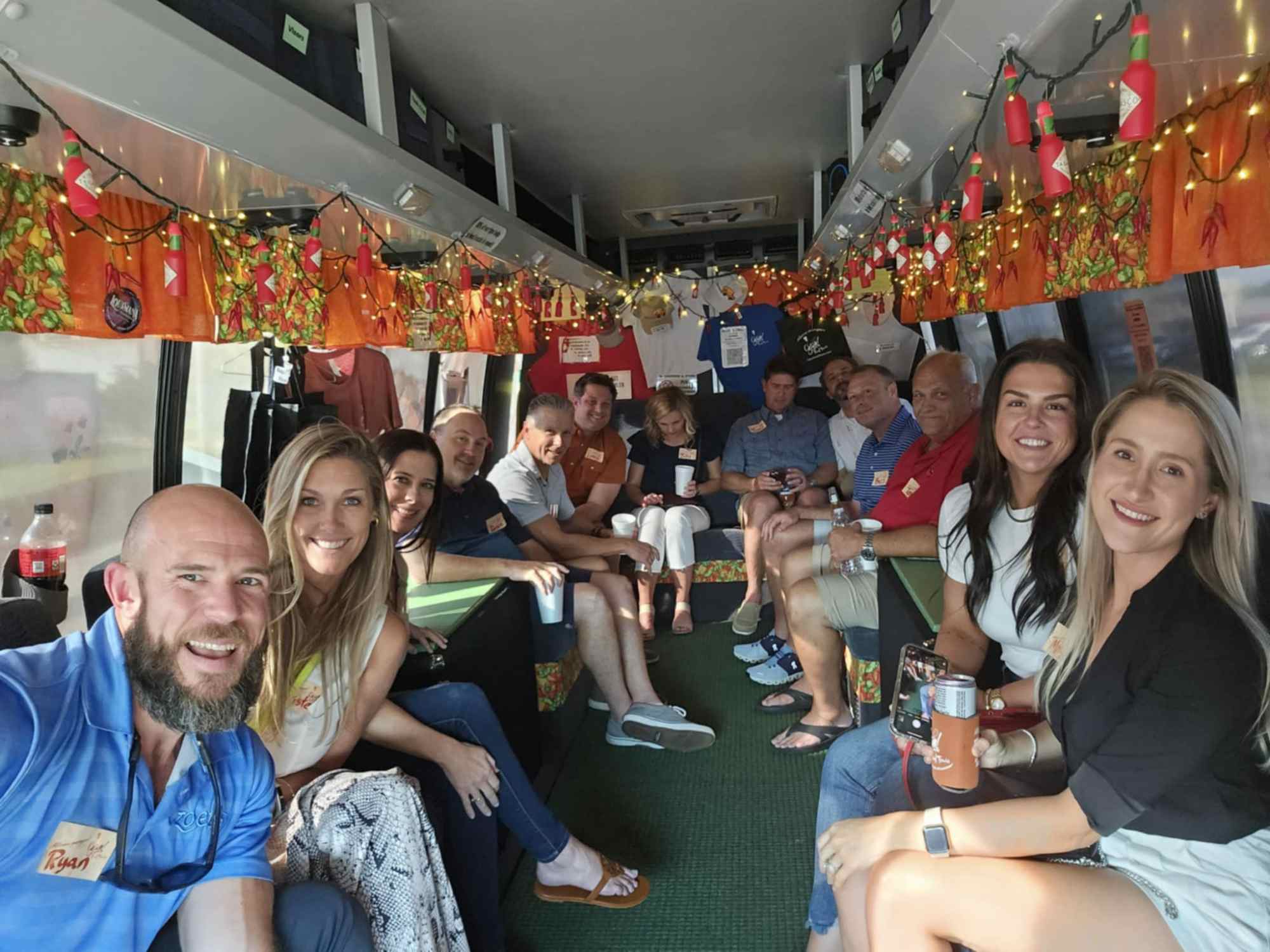 Group of people smiling inside a decorated bus with lights and colorful decorations on the ceiling.