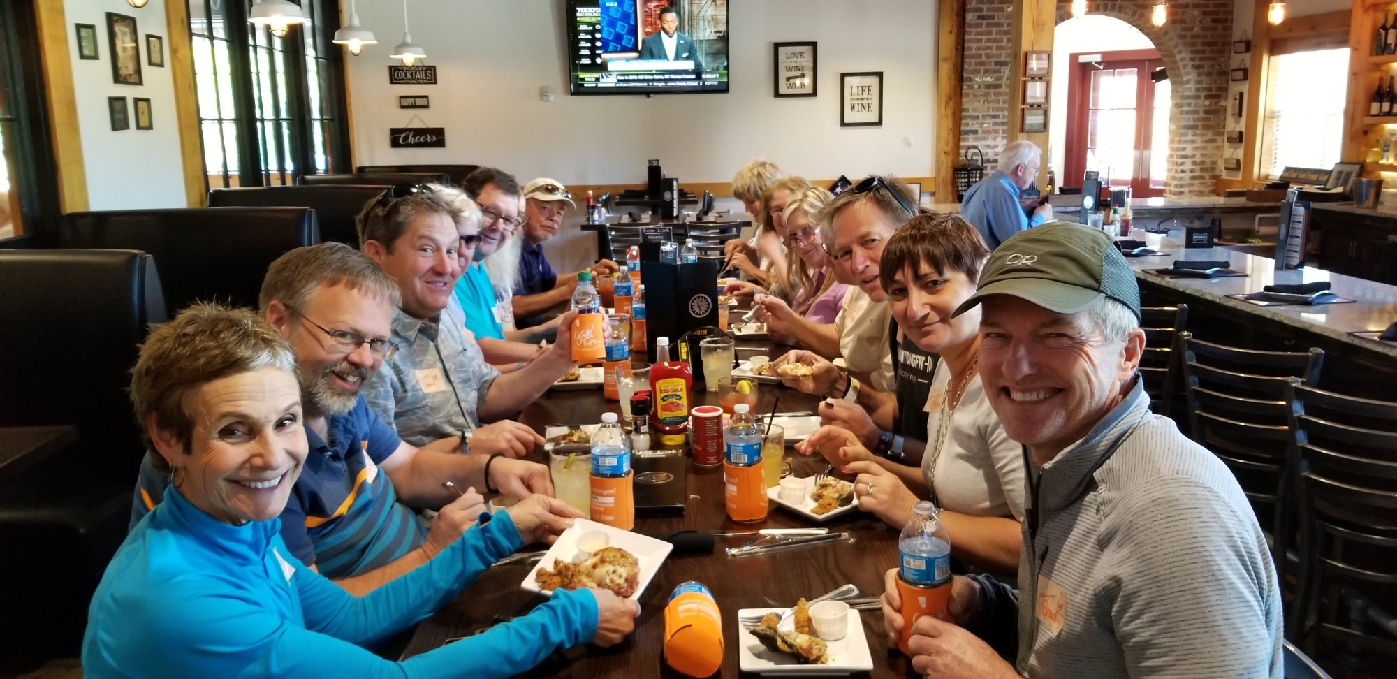 Group of people smiling and eating at a restaurant table.